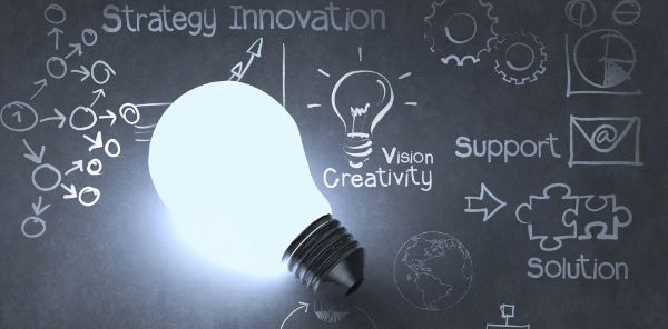 Lightbulb and chalkboard with a written strategy to drive growth including strategy and support.